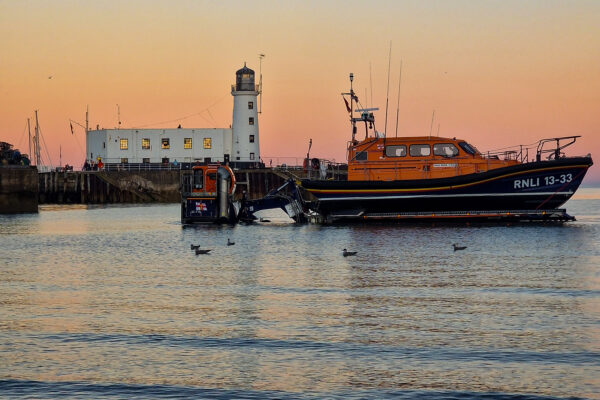 lighthouse and RNLI lifeboat in the sunset at Scarborough harbour